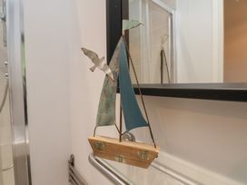 A metal and wood sailboat decoration hanging on a glass shelf bracket in a bathroom at Coastguards View in Whitby