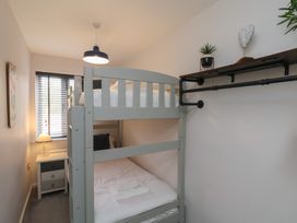 A small bedroom with a bunk bed a bedside table with a lamp and a wall shelf with plants at Coastguards View in Whitby