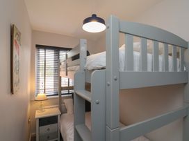 A small bedroom with a grey bunk bed a bedside table with a lamp and a window with blinds at Coastguards View in Whitby