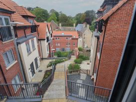 View of a residential area with brick and cream buildings with red tile roofs and a pathway with stairs and railings between them at Coastguards View in Whitby