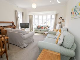 A living room with sofas pillows a television and a wooden cabinet at Seawinds 2a in Rhos-On-Sea