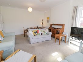 A living room with sofas a dining table wooden sideboard and a television at Seawinds 2a in Rhos-On-Sea