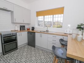 A kitchen with white cabinets wooden countertops patterned tile floor and two gray stools at Seawinds 2a in Rhos-On-Sea