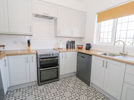 A kitchen with white cabinets patterned floor a stove dishwasher and a sink at Seawinds 2a in Rhos-On-Sea