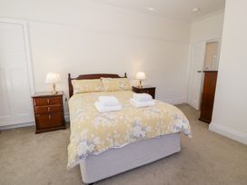 A bedroom with a double bed with floral bedding and two bedside tables with lamps at Seawinds 2a in Rhos-On-Sea