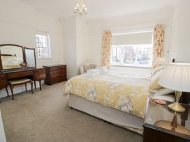 A bedroom with a bed and bedside table with lamps and a dresser with mirror at Seawinds 2a in Rhos-On-Sea