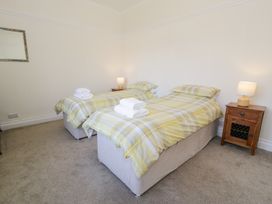 A bedroom with two single beds with yellow plaid bedding and wooden bedside tables with lamps at Seawinds 2a in Rhos-On-Sea