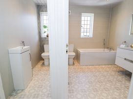 A bathroom with two toilets separated by a wall a bathtub and sinks at Seawinds 2a in Rhos-On-Sea