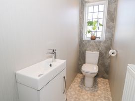 A small bathroom with a toilet and a sink below a window with a plant on the windowsill at Seawinds 2a in Rhos-On-Sea