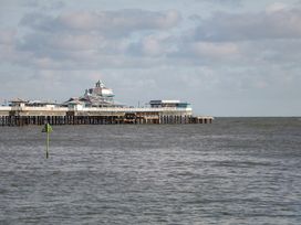 A pier extending over the sea with buildings on it under a cloudy sky at Seawinds in Rhos-On-Sea