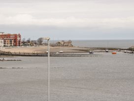 A coastal area with boats docked near a beach and buildings in the background at Seawinds in Rhos-On-Sea