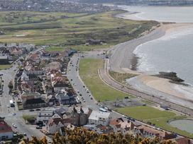 A coastal town with houses along a road next to a beach and green fields at Seawinds in Rhos-On-Sea