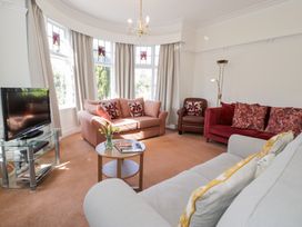 A living room with sofas armchair small round table and television at Seawinds in Rhos-On-Sea