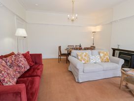 A living room with sofas, a dining table with chairs, a chandelier, floor lamps, and a fireplace at Seawinds in Rhos-On-Sea