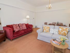 A living room with red and gray sofas and a wooden coffee table with magazines and flowers at Seawinds in Rhos-On-Sea