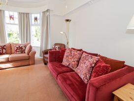 A living room with two sofas a leather chair and a window with curtains at Seawinds in Rhos-On-Sea