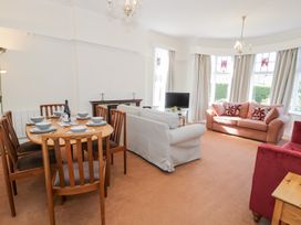 A living room with a dining table set with dishes wooden chairs two sofas a television and bay windows at Seawinds in Rhos-On-Sea