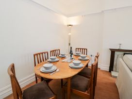 A dining room with a wooden table set for six with bowls plates and cutlery at Seawinds in Rhos-On-Sea