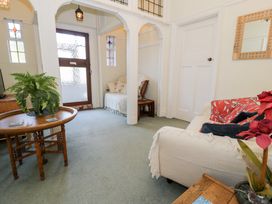 An entryway with a wooden door, a round wooden table with a plant, and seating areas with sofas and cushions at Seawinds in Rhos-On-Sea