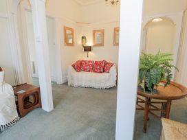 A sitting area with a white covered sofa and red cushions next to a wooden table with a potted fern at Seawinds in Rhos-On-Sea