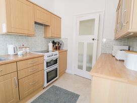 A kitchen with wooden cabinets a white stove a kettle and a toaster at Seawinds in Rhos-On-Sea