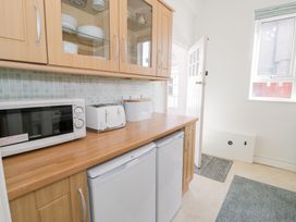 A kitchen with microwave toaster and bread bin on wooden counter with cabinets above and fridges below at Seawinds in Rhos On Sea