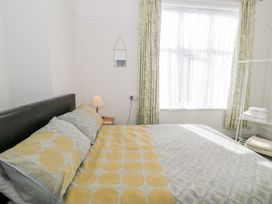 A bedroom with a bed pillow lamp small mirror and folded towels on a shelf at Seawinds in Rhos-On-Sea