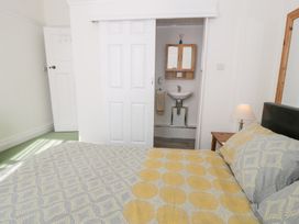 A bedroom with a bed and a bedside table with a lamp and a door leading to a bathroom at Seawinds in Rhos-On-Sea