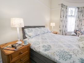 A bedroom with a bed covered with white and blue floral bedding and wooden bedside tables with lamps at Seawinds in Rhos-On-Sea