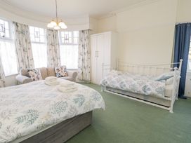 A bedroom with a double bed towels a single bed a sofa and a wardrobe at Seawinds in Rhos On Sea