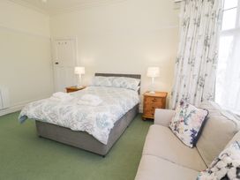 A bedroom with a bed with folded towels bedside tables with lamps and a sofa with patterned cushions at Seawinds in Rhos On Sea