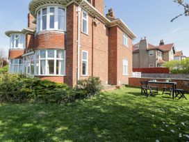 A brick house with bay windows and a garden with a table and chairs at Seawinds in Rhos-On-Sea