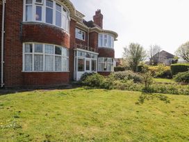 An exterior view of a brick house with large bay windows and a garden with grass and shrubs at Seawinds in Rhos-On-Sea