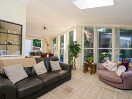 A living room with a black leather sofa and pink armchair next to large windows at RoseGrace Lodge in Auchterarder