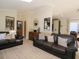 A living room with two leather sofas a wooden sideboard and a dining area in the background at RoseGrace Lodge in Auchterarder