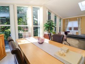 A dining table with chairs and a purple candle holder near large windows with a view of greenery at RoseGrace Lodge in Auchterarder