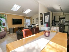 An open plan living room and kitchen with a dining table in the foreground at RoseGrace Lodge in Auchterarder