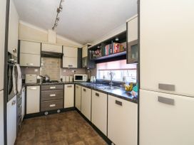 A kitchen with cabinets a sink a microwave and a stove at RoseGrace Lodge in Auchterarder