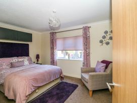A bedroom with a double bed floral curtains and an armchair at RoseGrace Lodge in Auchterarder