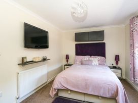 A bedroom with a bed a wall-mounted TV and floral curtains at RoseGrace Lodge in Auchterarder