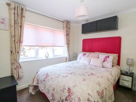 A bedroom with a bed featuring butterfly bedding and pink pillows next to a window with floral curtains at RoseGrace Lodge in Auchterarder