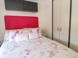 A bedroom with a bed with butterfly and horse patterned bedding and pink headboard at RoseGrace Lodge in Auchterarder