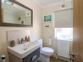 A bathroom with a sink and mirror toilet window with blind and radiator at RoseGrace Lodge in Auchterarder