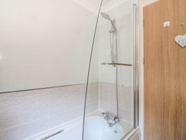 A bathroom with a bathtub shower combination and a wooden door at RoseGrace Lodge in Auchterarder