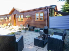 An outdoor patio area with wicker chairs and a table next to a wooden lodge at RoseGrace Lodge in Auchterarder