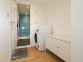 A laundry area with a washing machine and a storage cabinet leading to a bathroom with blue tiles