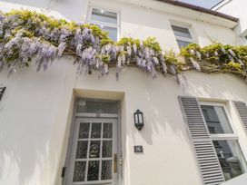 The exterior of a house with a door numbered 16 purple flowers growing above the entrance and windows with shutters at Saltwater Cottage in Babbacombe