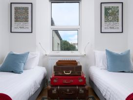 A bedroom with two single beds a window between them and three stacked suitcases as a bedside table at Saltwater Cottage in Babbacombe