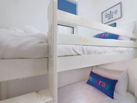 A bunk bed with white bedding and hoooray pillows in a bedroom at Saltwater Cottage in Babbacombe
