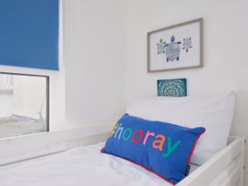 A bedroom with a white bed and a blue pillow with hooray text at Saltwater Cottage in Babbacombe
